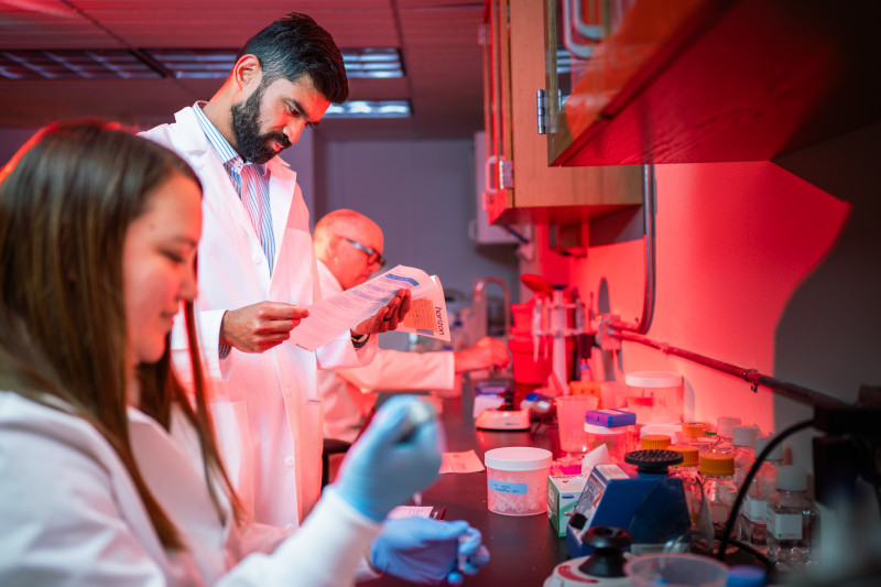 UW researchers stand along a counter in a lab.