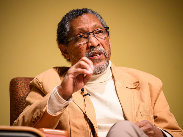 Percival Everett sitting in a chair, gesturing as he talks.